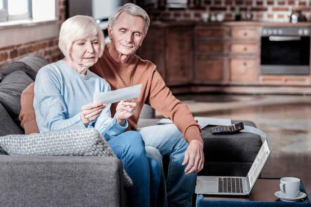 Foto: Älteres Ehepaar auf Couch betrachtet Brief